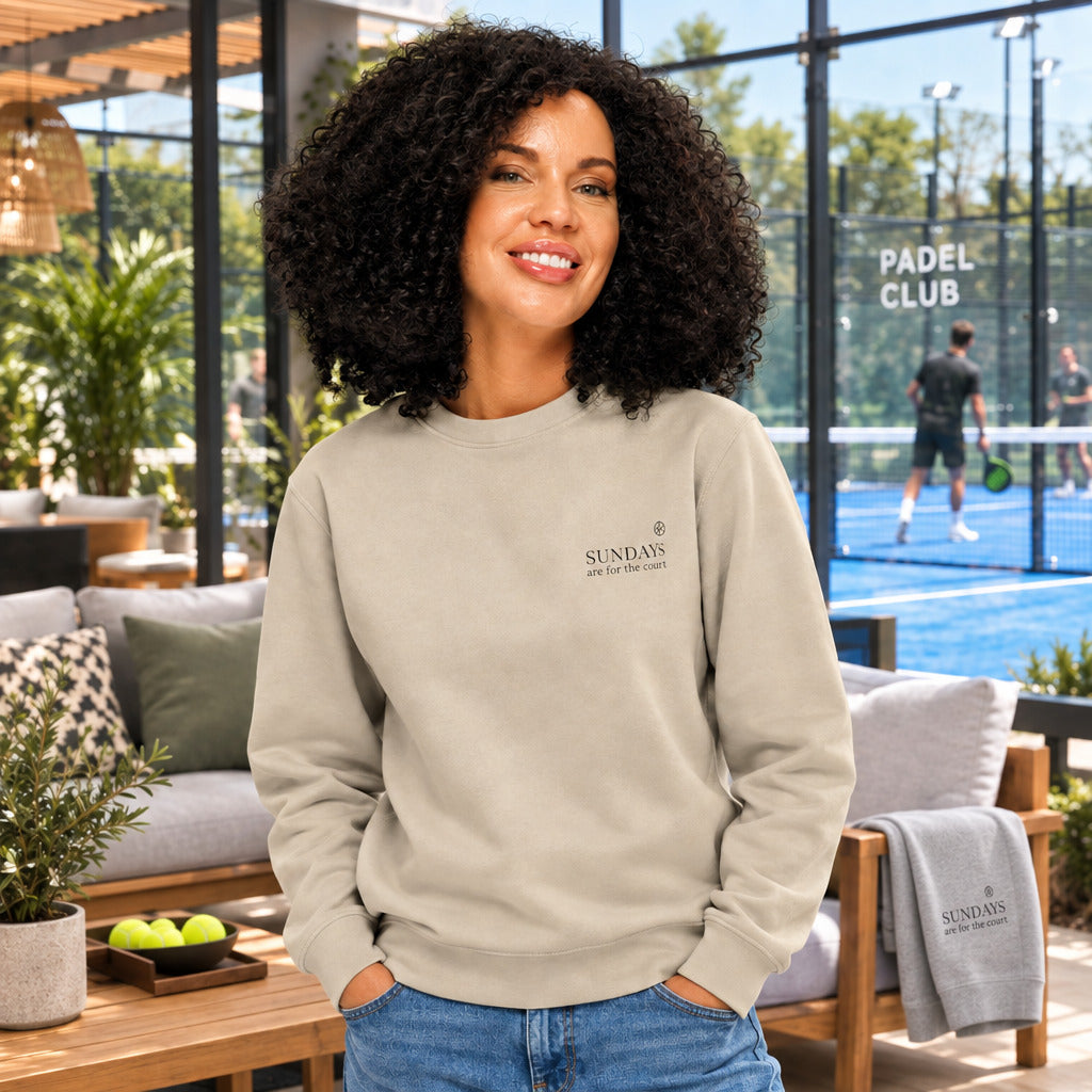 Sweatshirt für Padel Tennis und Tennis Spieler, kuscheliger Pullover vor und nach dem Training. Frau steht nach dem Training im Padel Tennis Outfit vor einem Padel Club Platz.